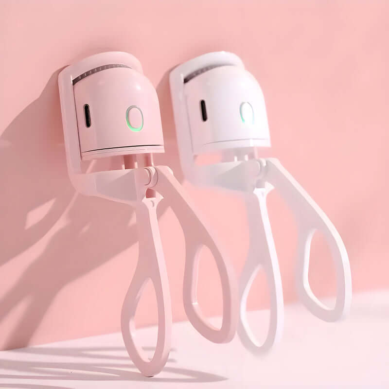 Rechargeable mini electric eyelash curlers in pink and white against a soft pink background.